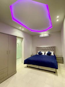 利雅德的住宿－شاليه الماسيه خاص و مميز بأحدث المواصفات لنصنع الجمال بعينه，一间卧室配有蓝色的床和紫色天花板