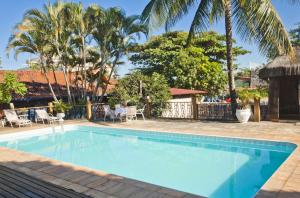 a swimming pool at a resort with palm trees at Quari Quara BY MN Hotéis in Rio das Ostras