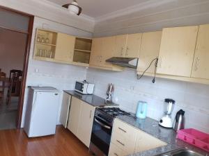 a kitchen with a stove and a white refrigerator at SERENITAS ApartHotel in Kigali