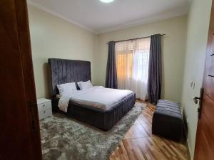 um quarto com uma cama e uma grande janela em Jay's Villa em Kampala