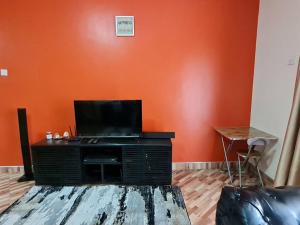 uma sala de estar com uma parede laranja e uma televisão de ecrã plano em Jay's Villa em Kampala