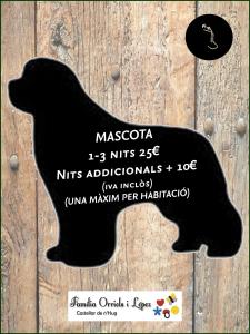 a black dog shaped sign on a wooden door at Hostal Les Fonts in Castellar de NʼHug