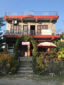 a building with an umbrella and a table and stairs at Hotel Sweetland in Sauraha