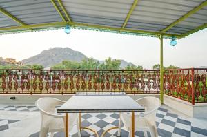 a table and chairs on a balcony with a view at Hotel Karohi Villa in Udaipur