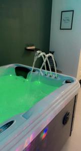 een groen bad met water er uit spuiten bij Zen Ô Spa in Charleroi