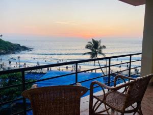 een balkon met uitzicht op het strand bij zonsondergang bij Karma Beach Resort in Kovalam