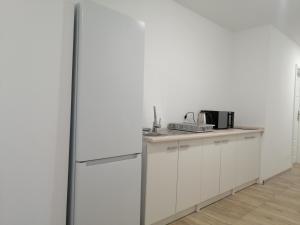 a kitchen with white cabinets and a refrigerator at Noclegi u Eugenii in Licheń Stary