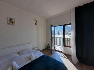 a bedroom with a large bed and a balcony at "White House Nakani" - Guesthouse near the centre in Mestia
