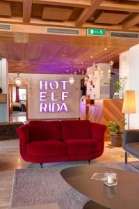 a living room with a red couch in front of a sign at Frida am Wald in Rasùn di Sotto