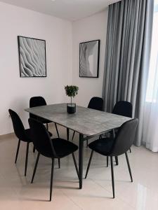 a dining room table with black chairs and a table with a plant on it at Stylish 2 bdr in Dubai Marina & hotels beach access available in Dubai