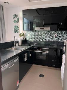 una cocina con armarios negros y fregadero en Stylish 2 bdr in Dubai Marina & hotels beach access available en Dubái