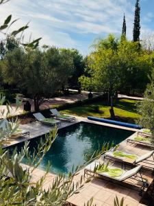 - une piscine entourée de chaises et d'arbres dans un parc dans l'établissement LES JARDINS DE MARRAKECH, à Marrakech