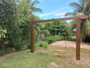 a swing set in a garden with palm trees at CORVINA SUMMER HOUSE in Guarajuba