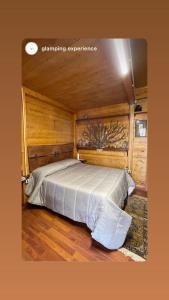 Rogliano的住宿－CHALET NEL BOSCO - TENUTA BOCCHINERI，木制客房内的一间卧室,配有一张床