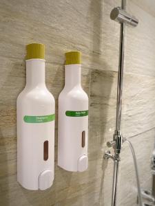 due bottiglie bianche sedute su un muro in una doccia di alfar Hotel a Dayuan