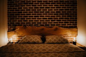 um quarto com uma parede de tijolos e uma cama com duas almofadas em DOUX Apartman em Odorheiu Secuiesc