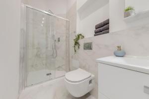 een witte badkamer met een douche en een toilet bij Kaizl Park Residence in Praag