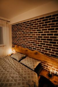 um quarto com uma cama com uma parede de tijolos em DOUX Apartman em Odorheiu Secuiesc