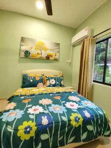 ein Schlafzimmer mit einem Bett mit einer blauen Decke mit Blumen in der Unterkunft JC HOMESTAY PORT DICKSON in Port Dickson