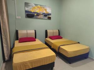2 Betten nebeneinander in einem Zimmer in der Unterkunft JC HOMESTAY PORT DICKSON in Port Dickson