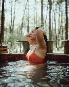 a woman sitting in a pool of water at RUKAKUTRAL refugio de bosque in Pucón