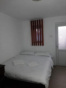 a white bedroom with a bed and a window at Vila Dionysos Brasov in Braşov
