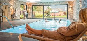 a woman sitting in a chair in front of a swimming pool at Hotel Spoorzicht & SPA in Loppersum