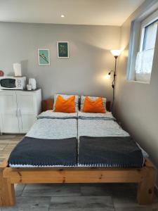 Charmant studio á Autrans في أوترانس: سرير مع وسادتين برتقاليتين في الغرفة