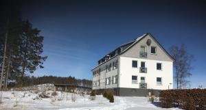 a large white building with a black roof in the snow at Steigerhaus Sauerland in Bestwig