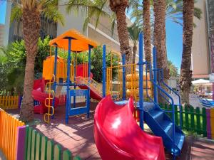 een speeltuin met een glijbaan in een park met palmbomen bij Hotel Servigroup Calypso in Benidorm