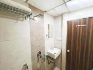 a bathroom with a sink and a wooden door at Hotel Avion Park - Near Mumbai International Airport in Mumbai