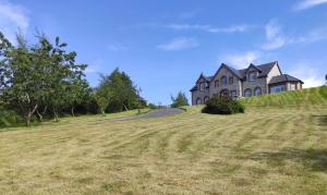 a large house on top of a grassy hill at Ballylawn Lodge in Letterkenny