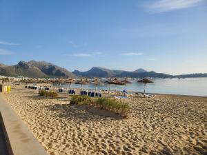 een strand met parasols en stoelen en het water bij Blick auf Atalaya in Port de Pollença