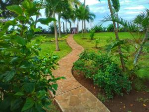 a path through a park with palm trees at Villa Colibri in Nosy Be