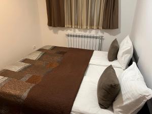 um quarto com uma cama com almofadas em Family apartmans Hari - Apart Hotel & spa Zoned, Kopaonik - Children up to 13 years free! em Kopaonik