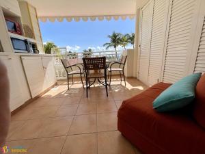 圣安尼Village Vacances Sainte Anne - Vue exceptionnelle Piscine et Plage Vue mer - Barbadine 1010 by Studios Barbadine的阳台设有带桌椅的客厅