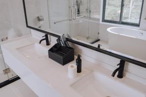 a white bathroom with two sinks and a mirror at Fan's Hotel in Baybay
