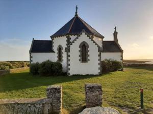 an old church on a grassy field with the ocean behind it at Centre ville de Sarzeau, appartement au calme avec jardinet et parking privé in Sarzeau +12 photos
