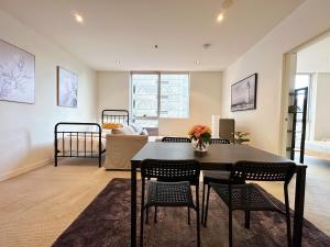 a living room with a table and chairs at Luxe Central City QV Apartment with Indoor Pool & Gym in Melbourne