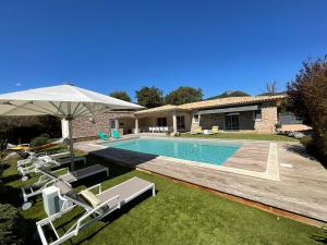 una casa con piscina con sedie e ombrellone di Villa Poggio Rosso - Pool-House & Piscine chauffée a Sainte-Lucie de Porto-Vecchio
