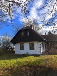 une petite maison blanche avec un toit noir dans l'établissement Őrségi Mi Kis Házunk vendégház, à Szalafő