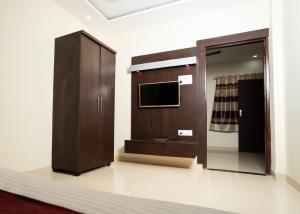 a living room with a tv and a wooden cabinet at Hotel Maya palace in Bhopal