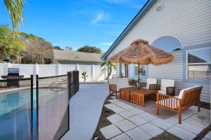 a patio with a table and an umbrella next to a pool at Jax Beach Luxury Oasis W/ Private Pool/Jacuzzi Tub in Jacksonville Beach