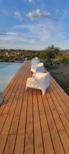 una fila de sillas blancas sentadas en una terraza de madera en BLACK BOX CABAÑAS A en Villa Santa Cruz del Lago