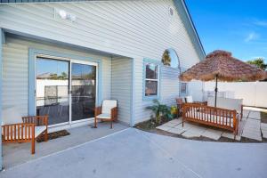 un patio con 2 bancos y una sombrilla en Jax Beach Luxury Oasis W/ Private Pool/Jacuzzi Tub, en Jacksonville Beach