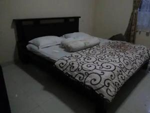 1 cama con edredón y almohadas en blanco y negro en Villa Kota Bunga C - Puncak, en Pacet