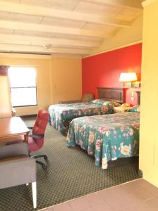 a hotel room with two beds and a desk and a chair at Scottish Inn - Nashville in Nashville