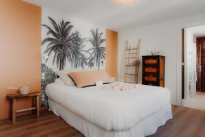 a bedroom with a large white bed with palm trees on the wall at Hôtel PALMITO in Biarritz