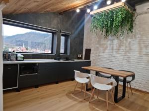 eine Küche mit einem Holztisch und weißen Stühlen in der Unterkunft Casa Chiper - Attic apartment with view in Braşov