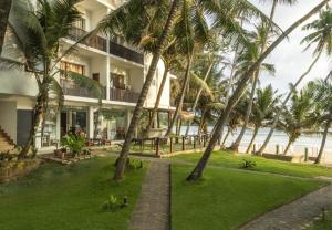 a building with palm trees in front of the ocean at Dickwella Beach in Dickwella